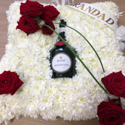 Cushion  - Made with white basing chrysanthemums and your loved ones favourite tippel placed in the centre of the display 